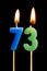 Burning candles in the form of 73 seventy three numbers, dates for cake isolated on black background. The concept of celebrating