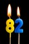 Burning candles in the form of 82 eighty two numbers, dates for cake isolated on black background. The concept of celebrating a