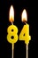 Burning candles in the form of 84 eighty four numbers, dates for cake isolated on black background. The concept of celebrating a