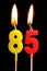 Burning candles in the form of 85 eighty five figures numbers, dates for cake isolated on black background. The concept of cel