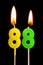 Burning candles in the form of 88 eighty eight numbers, dates for cake isolated on black background. The concept of celebrating