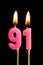 Burning candles in the form of 91 ninety one numbers, dates for cake isolated on black background. The concept of celebrating a