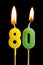 Burning candles in the form of eighty figures numbers, dates for cake on black background. The concept of celebrating a