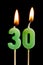 Burning candles in the form of thirty figures numbers, dates for cake on black background. The concept of celebrating a