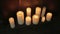 Burning candles near a metal wall on wooden floor. Slow panning zoom.