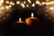 Burning candles over black background with bokeh glitter lights
