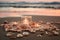 Burning candles and pink rose petals on a sandy beach. AI generated.