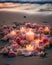 Burning candles and pink rose petals on a sandy beach. AI generated.