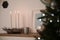 Burning candles on shelf near Christmas tree