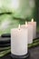 Burning candles, spa stones and bamboo sprouts on grey table against green background