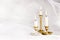 Burning candles in vintage metal candlesticks on white abstract white tulle material  background.
