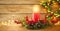 Burning Christmas red candle and  festive Christmas arrangement on a wooden table