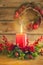 Burning Christmas red candle and  festive Christmas arrangement on a wooden table