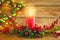 Burning Christmas red candle and  festive Christmas arrangement on a wooden table