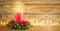 Burning Christmas red candle and  festive Christmas arrangement on a wooden table