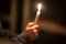 burning church candles in the hands of children on a dark background