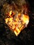 Burning crumbling heart on the rock background.