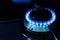 Burning gas stove blue flames close up in the dark on a black background