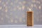 Burning gold candle on table against blurred lights.