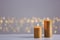 Burning gold candles on table against blurred lights