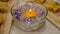 Burning heart-shaped candle floating in bowl with water and mauve flowers