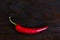 Burning hot vibrant red mexican chilli pepper. Hot spicy red chili peppers on a dark wooden background.