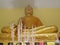Burning incense sticks in front of a gold Buddha statue with waving smoking