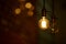 A burning light bulb glows faintly against the background of blurry yellow lights. Energy crisis. Blackout