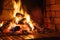 Burning logs and embers in a clay brick fireplace in a country cottage