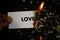 Burning love, human hand holding the word love written on a paper burning with flame and ashes on a black background