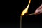 Burning match on a black background. A match sets fire to another match against a dark background.
