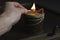 A burning match in the hand is lit by a cinnamon candle. In the dark