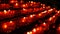 Burning memorial candles in Catholic church. Row of christian prayer red round votive candles burn in the dark. Prayer