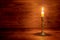 Burning old candle with vintage brass candlestick on wooden back