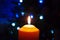 A burning orange candle on a dark background with blue lights - a Christmas New Year`s eve divination mystic esoteric romance lov