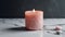 Burning pink candle on a white marble background. Copy space.