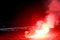 Burning red flare, flame, football hooligan. football fans lit up the lights and smoke bombs on the football pitch. Burning red fl