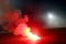 Burning red flare, flame, football hooligan. football fans lit up the lights and smoke bombs on the football pitch. Burning red fl