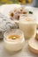 Burning scented candles, warm sweater and chamomile flowers on white wooden table, closeup