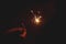 Burning sparking stick starlight fireworks pyrotechnic dark black warm background