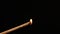 Burning stick with incense on a black background, set on fire from a wooden match