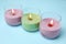 Burning wax candles in glass holders on light blue