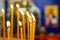 Burning wax candles in the temple. A fragment of a candlestick in a church with bright lights on the background of the icon. Close