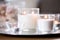 Burning white fragrance candles on tray on table