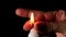 Burning white wax candle on a black background, hand extinguishes flame with fingers