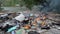 Burning wild garbage dump. Plastic bags, bottles, trash and rubbish near river. Heavily contaminated river bank. Environmental pol