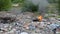 Burning wild garbage dump. Plastic bags, bottles, trash and rubbish near river. Heavily contaminated river bank. Environmental pol