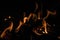Burning wood at night. Campfire at touristic camp at nature in mountains. Flame amd fire sparks on dark abstract