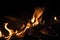 Burning wood at night. Campfire at touristic camp at nature in mountains. Flame amd fire sparks on dark abstract