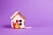 burning wooden model of a house, fire cut out of felt, purple background copy space